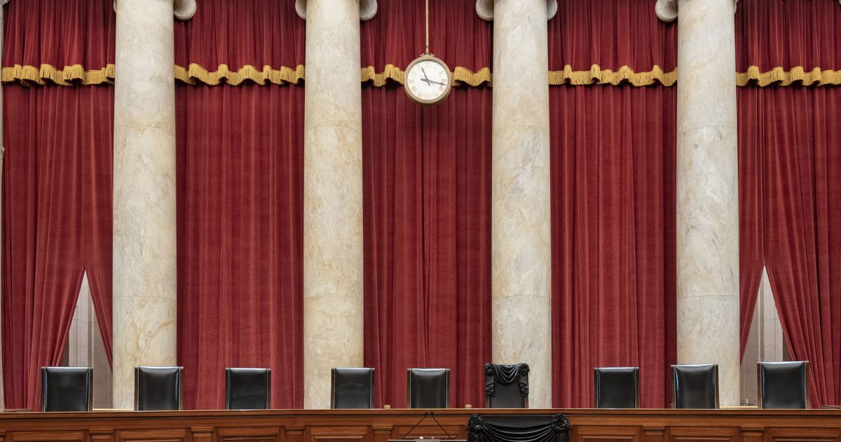 Courtroom of the Supreme Court with Associate Justice Ruth Bader Ginsburg’s chair and the bench in front of her seat draped in black.jpg